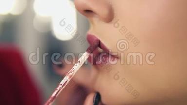 一位专业化妆师将口红涂在模特的嘴唇上，`从事美容时尚行业